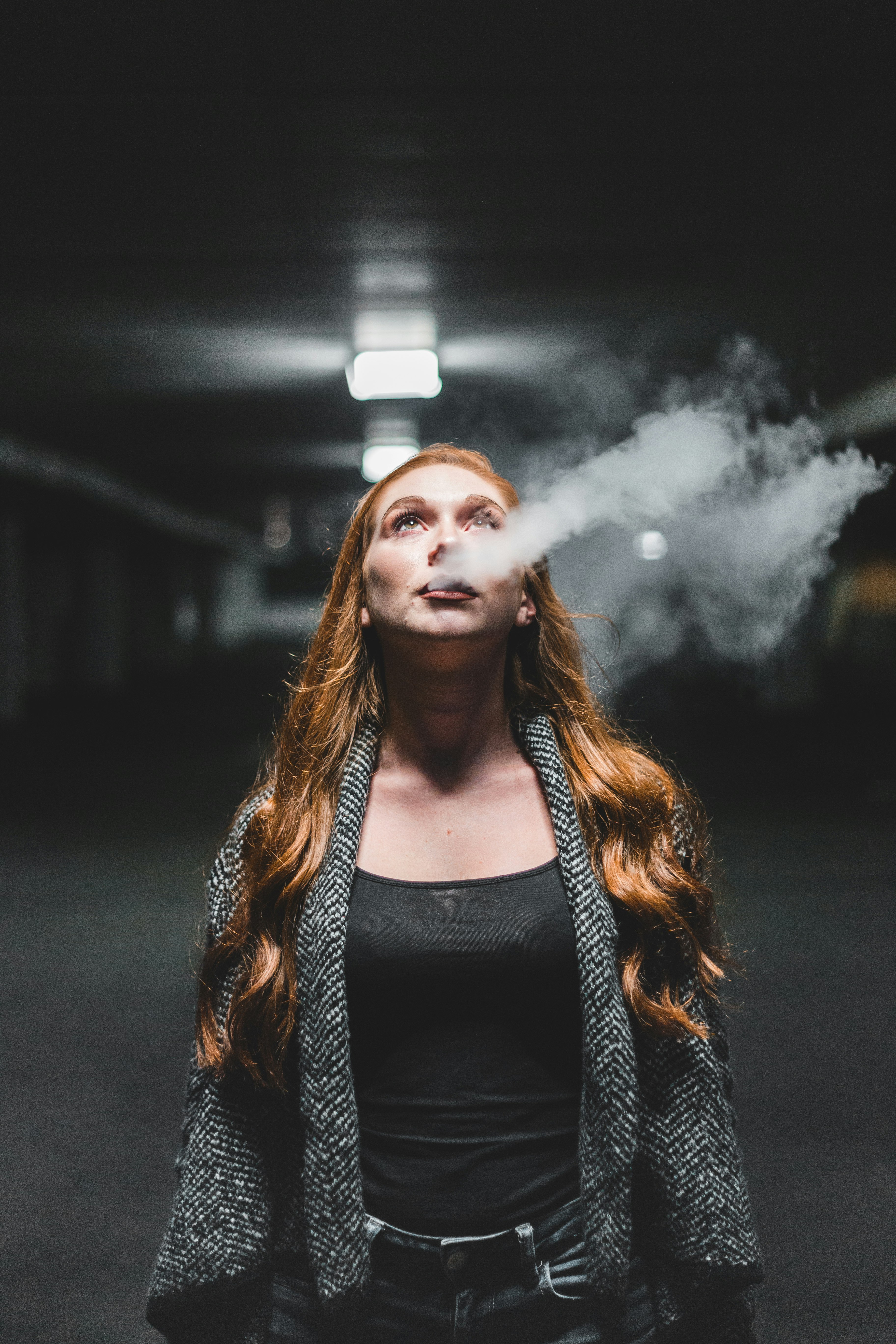 woman looking up while blowing smoke
